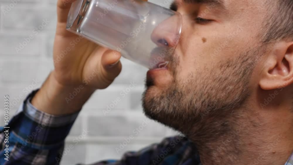 Close-up bearded man drinking milk from a glass. Slow motion. Side view. There is a light wall in the background. Fresh milk for breakfast Close-up bearded man drinking milk from a glass. Slow motion. Side view. There is a light wall in the background. Fresh milk for breakfast