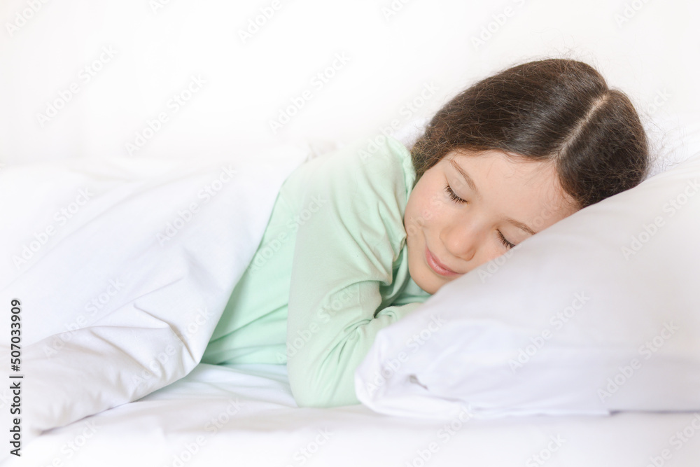 Beautiful cute girl with a smile on her face sleeps, rests in bed.