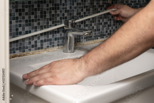 plumber removing old silicone from bathroom sink. hands close up photo