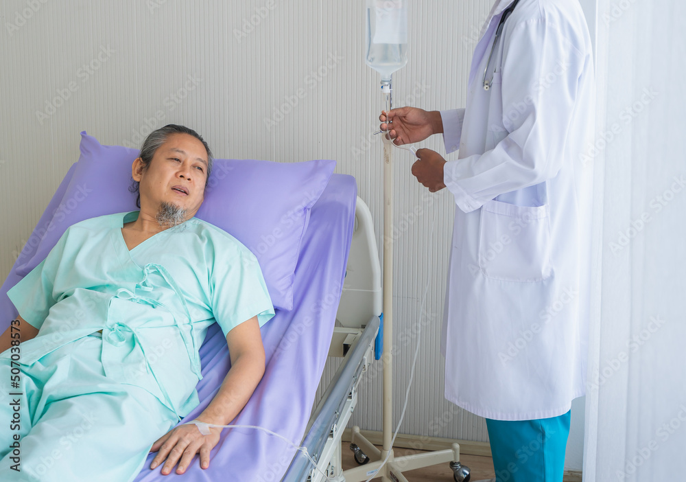 Obraz premium Elderly patient man unhappy, suffer, sadness from sick looking to outside window and doctor with stethoscope adjust saline. Doctor or nurse take care senior patient health admission at hospital