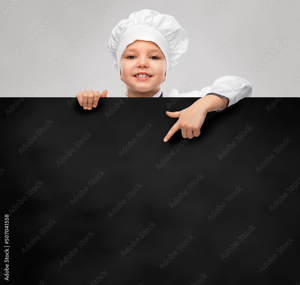 cooking, culinary and profession concept - happy smiling little girl in chef's toque and jacket with black board over grey background cooking, culinary and profession concept - happy smiling little girl in chef's toque and jacket with black board over grey background