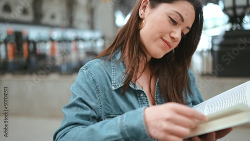 Pretty brunette woman tourist reading book on the bench