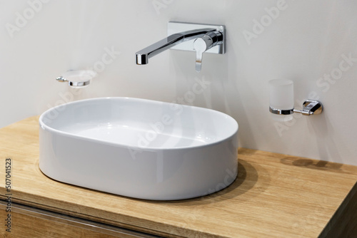 White sink with faucet on a wooden pedestal. Stylish Scandinavian design. Construction and repair.