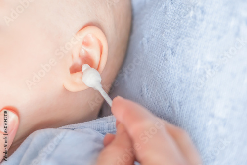 mother's hands cleaning baby's ears photo