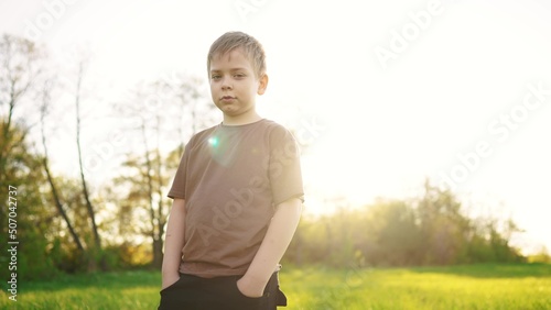 lifestyle little boy outdoor portrait. happy family kid a dream concept. child close-up in the park in nature looking to the side. boy kid portrait in the background grass forest park