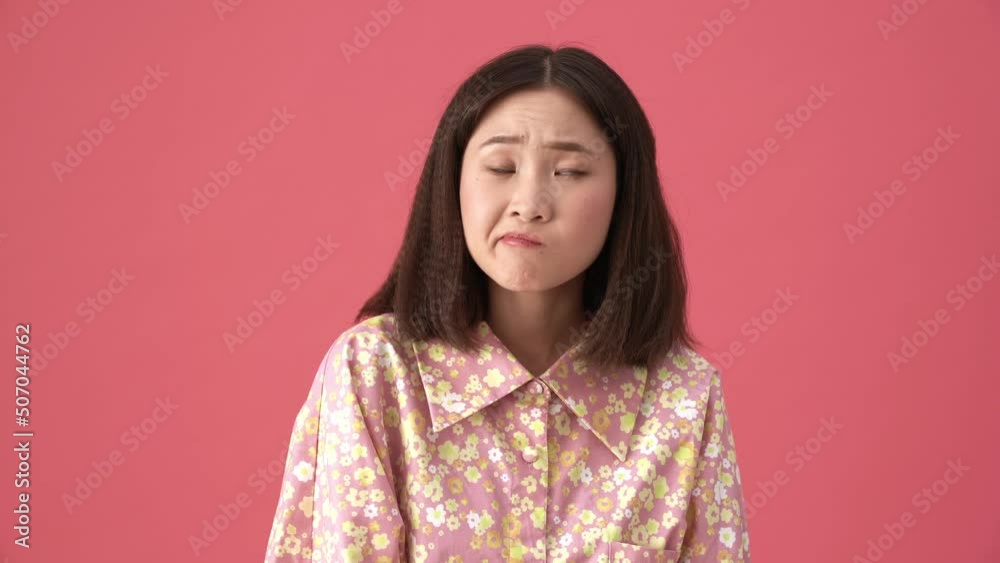 Pensive Asian woman thinking about something in the pink studio Pensive Asian woman thinking about something in the pink studio