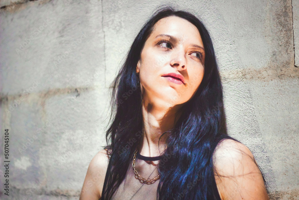 Fototapeta premium A goth girl leaning against a wall looking away from the camera