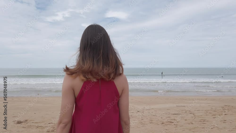 Young asian woman wear red dress and walking relaxing on the beach at summer vacation holidays in slowmotion Young asian woman wear red dress and walking relaxing on the beach at summer vacation holidays in slowmotion