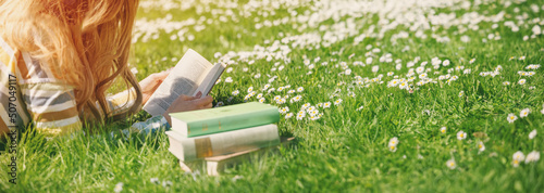 Young woman lying on the field and reading some books