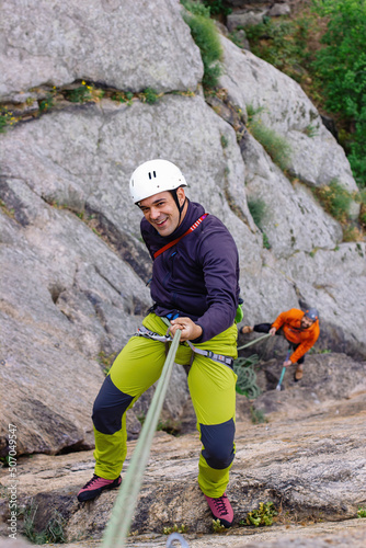 climbers smiling as they rappel down a wall photo