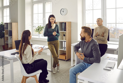 Dialogs or conversations between colleagues at workplace. Group of office workers who communicate or talk to each other during informal working conversation. Woman tells her idea about business. photo