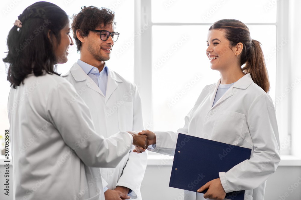 science, work and people concept - international group of happy scientists shaking hands in laboratory science, work and people concept - international group of happy scientists shaking hands in laboratory