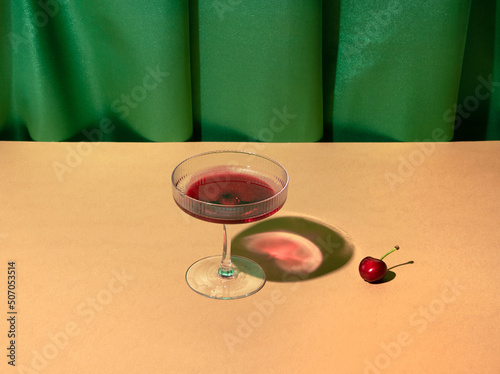 Cocktail glass against vintage rich green drapery. Old fashioned arrangement. 