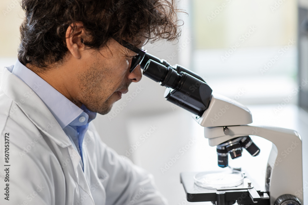 science research, work and people concept - close up of male scientist with microscope working in laboratory