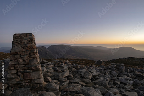 Fotografi Mountain camping scene with trig point and sunset over Snowdonia in Wales UK