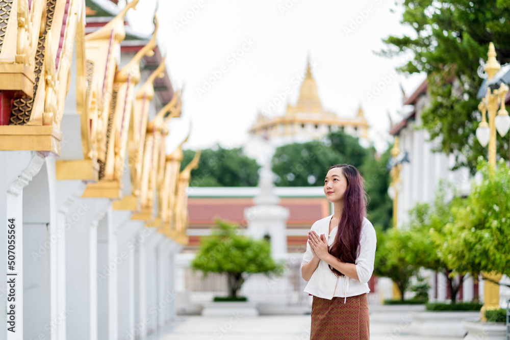 portrait Asian buddhist woman wearing traditional dress of Thailand praying at Wat Ratchanatdaram bangkok
