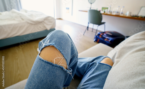 First person view of woman sitting in hotel room on a couch, legs in focus, room unfocused.