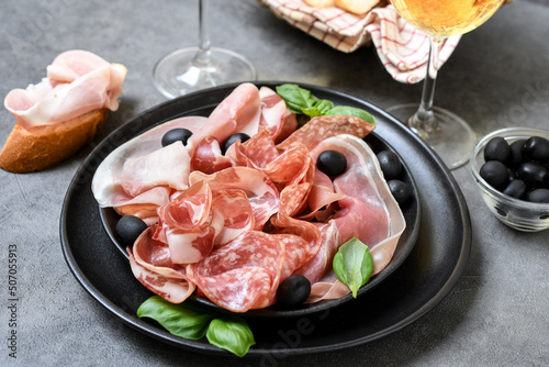 Food antipasto prosciutto ham, salami, olives and 
 bread . Charcuterie board. Two glasses of white wine or prosecco