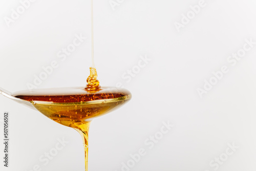 close up of honey being poured into a silver spoon, honey is a natural sweetener as a substitute for sugar