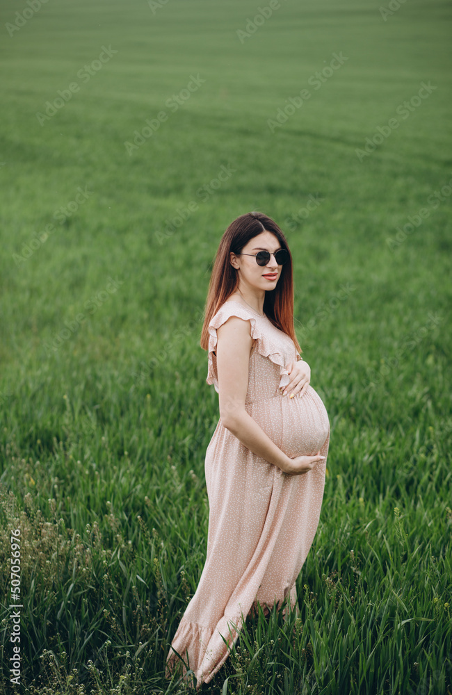 Pretty young pregnant woman relaxing outside in nature at summer day Pretty young pregnant woman relaxing outside in nature at summer day