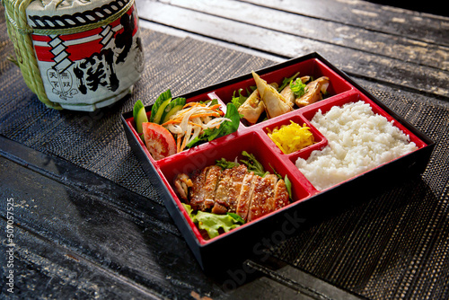 Photos Teriyaki chicken bento with dumplings and salad in the traditional Japanese rame