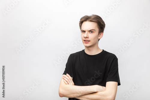 Suspicious young man with crossed arms studio shot on gray background photo