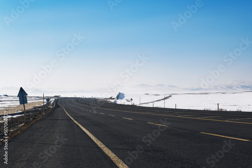View of an emtpy road with yellow lanes and snow in winter