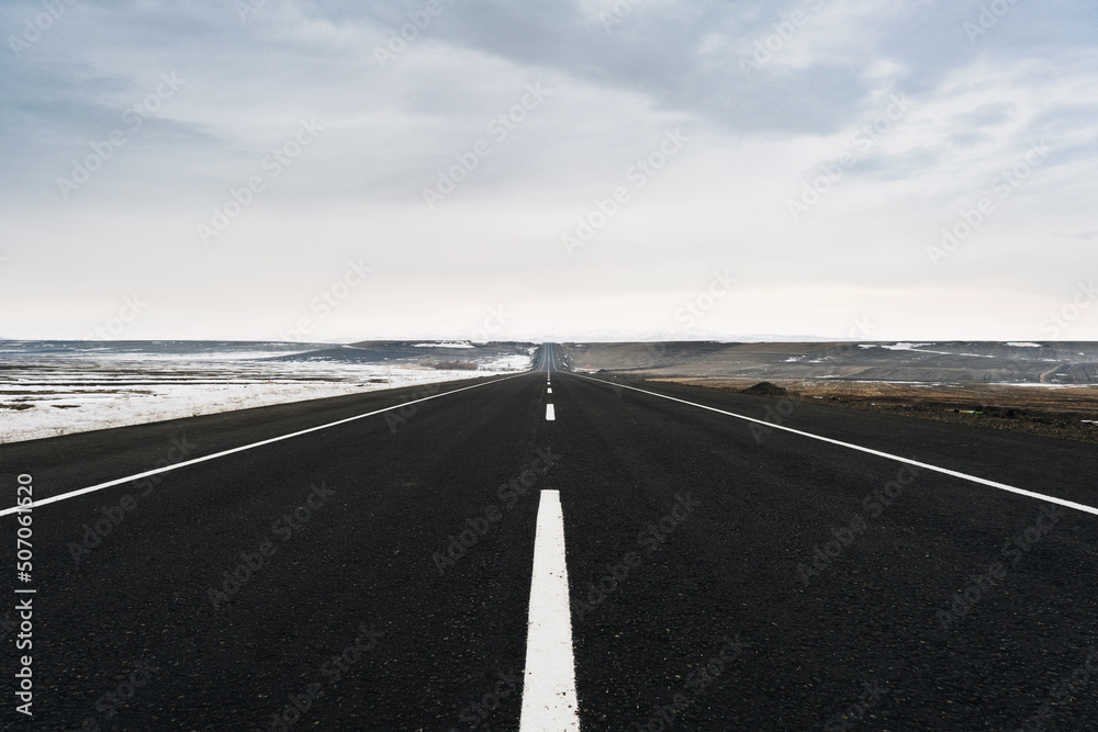 Fototapeta premium Close up View of an emtpy asphalt road with lanes and snow in winter