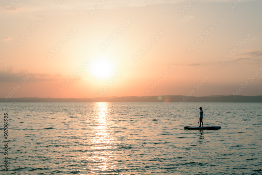 sunset at lake balaton, man floating on a board SUP