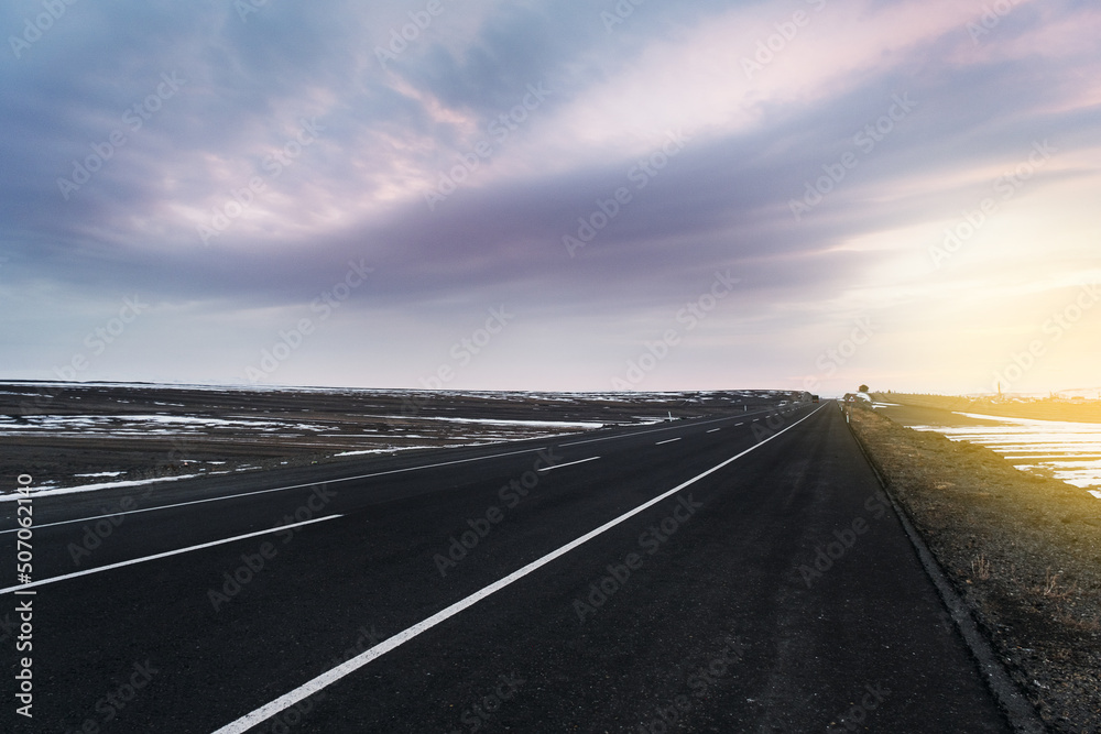 Diagonal view of an emtpy asphalt road with lanes and snow in winter