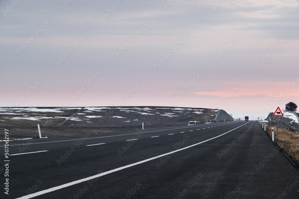 Diagonal view of an emtpy asphalt road with lanes and snow in winter