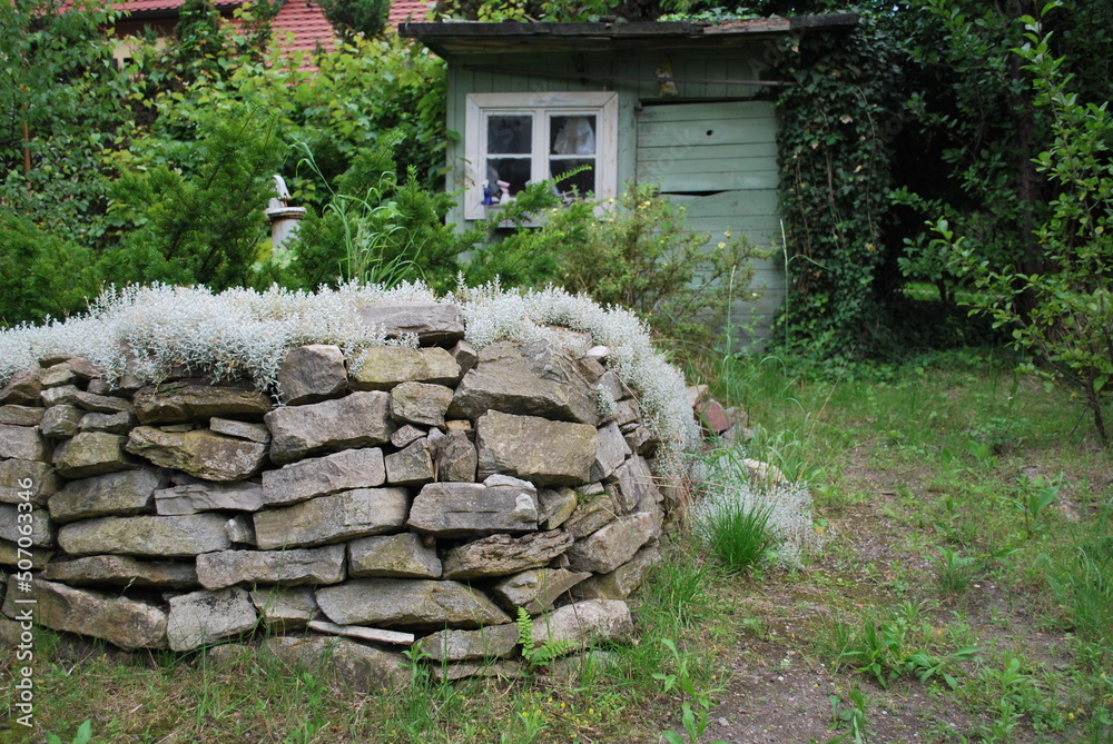 a stone wall, in the background an allotment box, a garden - obrazy, fototapety, plakaty 