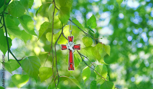 Christian cross with image of a dove on birch branches, abstract blurred green natural background. symbol of Holy Spirit. Holy Trinity Sunday, festive Pentecost day. Faith in God, Church holiday conce