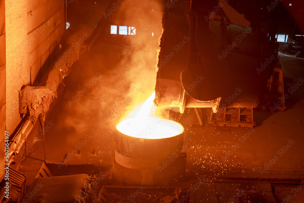 Obraz premium Hot steel pouring from big casting ladle into a mold in an iron foundry.