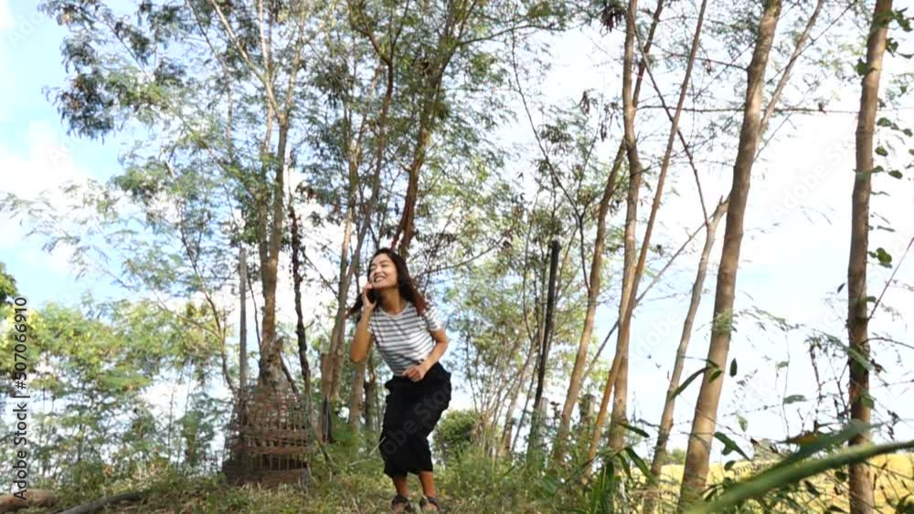 Asian woman talking on the phone and jumping with joy Asian woman talking on the phone and jumping with joy