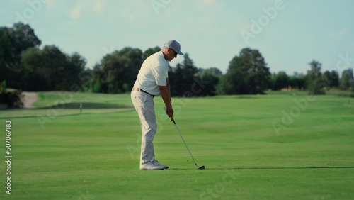 Old man play golf on grass fairway. Pro player swing club hitting ball outside. photo