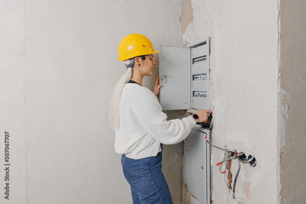 Women foreman architect check checking electrical panel and work of electrician in apartment