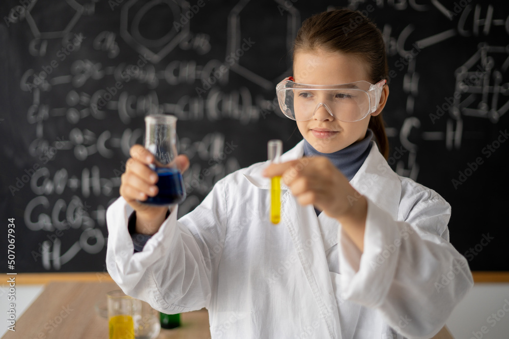 little scientist girl with glasses in lab coat with chemical flasks, on school blackboard background with science formulas, back to school little scientist girl with glasses in lab coat with chemical flasks, on school blackboard background with science formulas, back to school