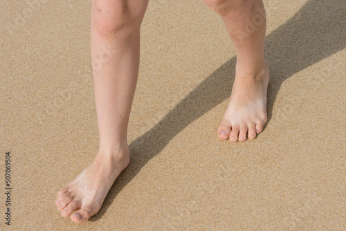 girl's bare feet walking in the sand