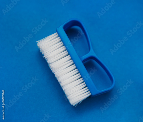 Close-up  cleaning brush on a blue background. A brush with a white pile and a blue handle. Convenient equipment for cleaning the house.