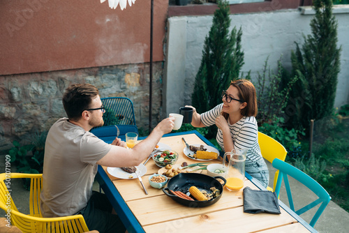 couple have lunch in backyard. they cheers with glasses