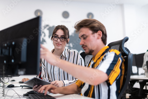 Business couple working together on project using tablet and desktop computer at modern open plan startup office. Selective focus 