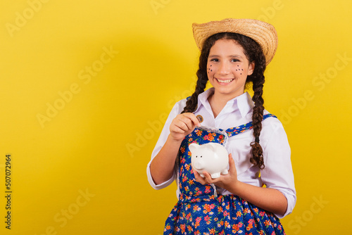 Girl wearing typical clothes for Festa Junina. Holding coin and piggy bank. For the Arraia party