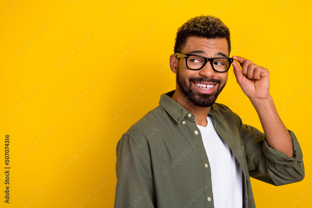 Photo of positive dreamy guy dressed green shirt hand eyewear looking back empty space isolated yellow color background Photo of positive dreamy guy dressed green shirt hand eyewear looking back empty space isolated yellow color background
