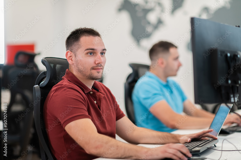 Obraz premium Group of Casual business man working on desktop computer in modern open plan startup office interior. Selective focus 