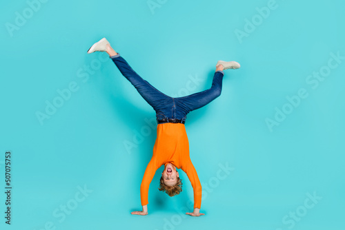 Full length photo of funky funny guy dressed orange sweater dancing walking arms isolated turquoise color background