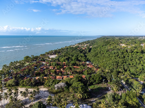 Wonderful paradise beach with the summer sun rising in the middle of the Atlantic Forest. Tourist town Arraial D'Ajuda, Brazil, South America. Aerial drone view.