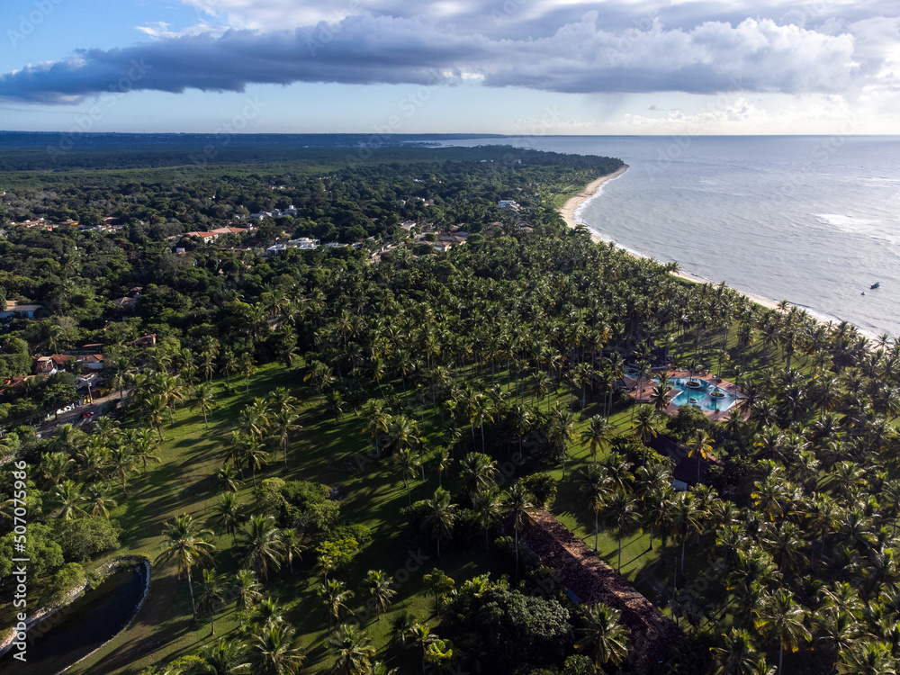 Obraz premium Wonderful paradise beach with the summer sun rising in the middle of the Atlantic Forest. Tourist town Arraial D'Ajuda, Brazil, South America. Aerial drone view.