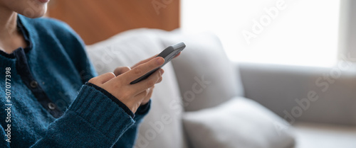 Close up of a woman using mobile smart phone on sofa at cozy home photo