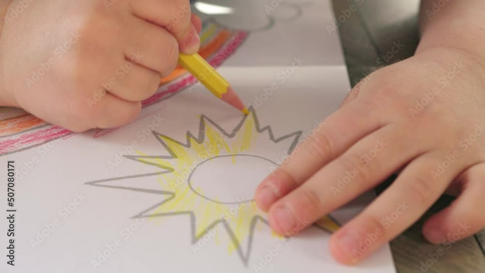 child baby kid hands drawing coloring yellow sun crayon, pattern color in pencil. concept of children creativity education, school art classes for preschool age concept. handwriting skills developing child baby kid hands drawing coloring yellow sun crayon, pattern color in pencil. concept of children creativity education, school art classes for preschool age concept. handwriting skills developing